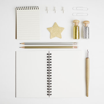 Clean and bright stationary mock-up: notebooks, foutain pen, pencils, gold and silver glitters, pins and stars on white background. Text space