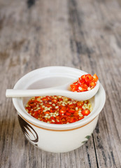 Homemade red Thai sauce with chopped chilli on wooden table at local cafe in Ching Mai, Norther Thailand. Traditional spicy food concept. Nam Prik. Text space