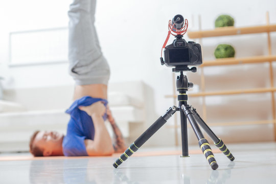 Modern camera. Experienced video blogger recording all the aspects of his yoga lesson while being on the floor in his room in front of a modern camera