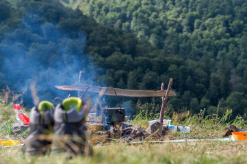 Cooking of a dinner over an open fire under the sky in a travel camping  in the summer mountains