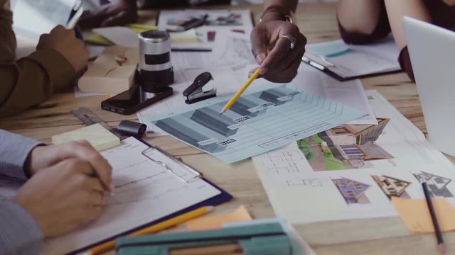 Young multiracial group of people working in coworking space. Small start-up of architects discussing the project ideas.