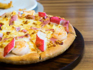 seafood pizza topping whit Crab, shrimp and ham On a wooden tray. The background is restaurant