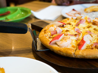 seafood pizza topping whit Crab, shrimp and ham On a wooden tray. The background is restaurant