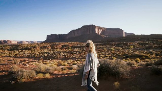 woman walking in Monument Valley with red rocks overview. Arizona