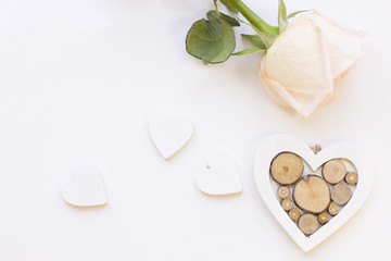 Obraz premium St. Valentine's Day concept with a beautiful white rose and wooden hearts, white background top view