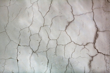 Textured surface of white wall with cracked plaster
