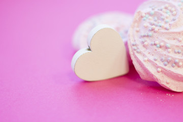 St. Valentine's Day or Anniversary concept with wooden heart and marshmellows, pink background, close up