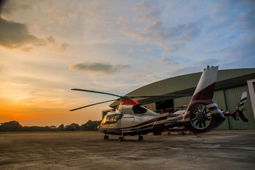 Fototapeta na wymiar silhouette of helicopter in the parking lot or runway with sunrise background,twilight helicopter on the helipad