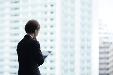 タブレットPCを使用する女性・都市風景バック