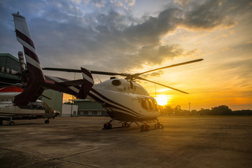 Silhouette des Hubschraubers auf dem Parkplatz oder der Landebahn mit Sonnenaufgangshintergrund, Dämmerungshubschrauber auf dem Hubschrauberlandeplatz