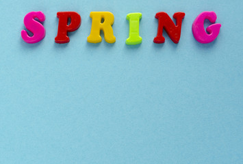 word "spring" of plastic magnetic letters on blue background