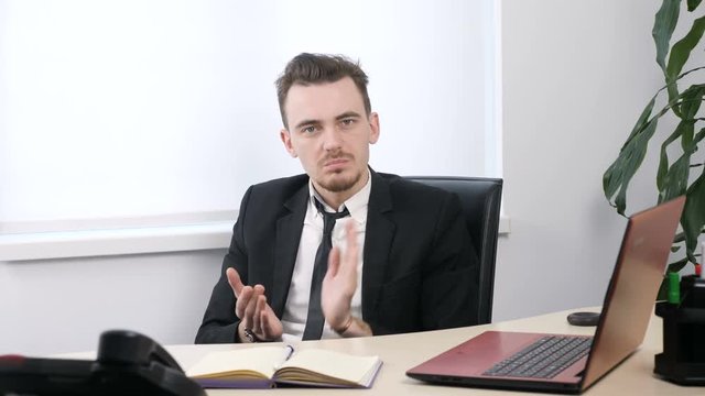 Young businessman in suit sitting in office and applauding, sarcasm, contempt 60 fps