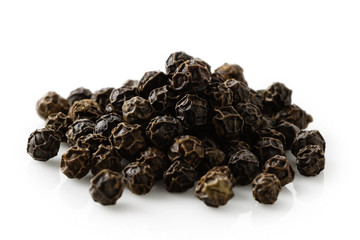 A pile of whole black pepper isolated on white.