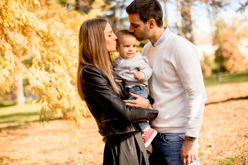 Fototapeta premium Happy young parents with baby boy in autumn park