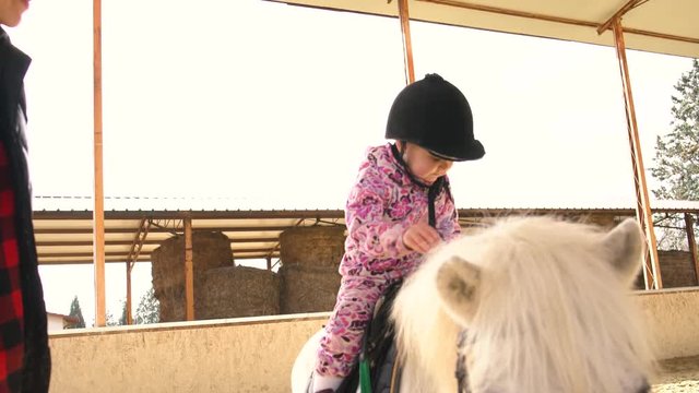Little girl sitting a pony in the arena 4K
