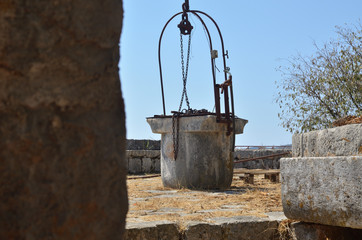 Old well made of stone in an abandoned coastal house front yard