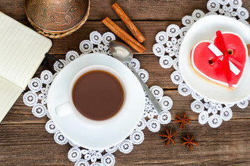 Cup of coffee, heart shaped cookies, a notebook with a pencil and coffee pots