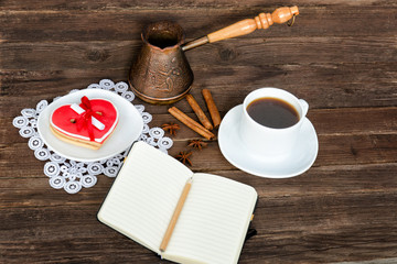 Notebook with a pencil, cup of coffee, heart shaped cookies and coffee pots