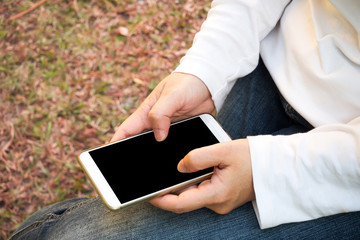 Woman using smart phone in park. Relaxing time with connecting on internet. Concept of favorite hobby in digital equipment.