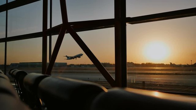 Silhouette of an airplane taking off at sunset at Beijing airport in the background of a window.