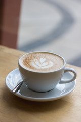 Hot coffee latte with beautiful foam art on glass table.Indoor cafe