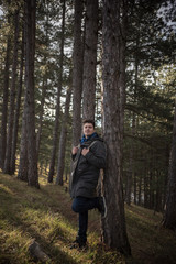 young man enjoying in forest while leaning on tree