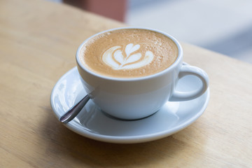 Hot coffee latte with beautiful foam art on glass table.Indoor cafe