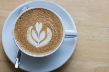 Hot coffee latte with beautiful foam art on glass table.Indoor cafe