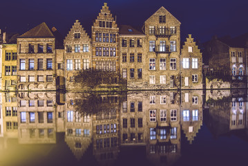 Fototapeta na wymiar Ghent, Flanders, Belgium - January 2th, 2017. Night Gent Old town view with illuminated medieval merchant houses reflected on the water of canal by evening lights. City illumination.