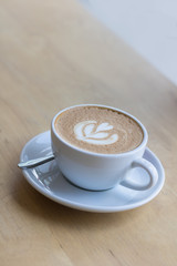 Hot coffee latte with beautiful foam art on glass table.Indoor cafe
