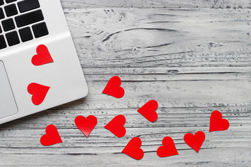 Background of a valentine on a wooden table with a laptop and hearts. Valentines Day greeting card. Top view