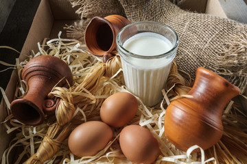 Clay jugs, eggs, glass of milk, on the straw and a burlap.