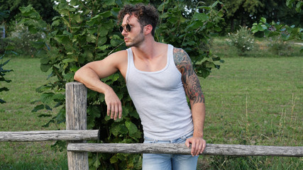Handsome Muscular Hunk Man Outdoor in Countryside Standing on Grass. Showing Healthy Muscle Body...