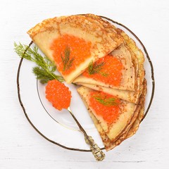 Pancakes with red caviar on a plate. On a wooden background. Top view. Free space for text.