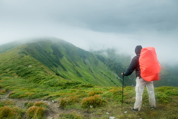 Fototapeta na wymiar Traveler with backpack in the mountains in the clouds