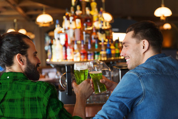 male friends drinking green beer at bar or pub