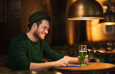 man with smartphone and green beer at bar or pub