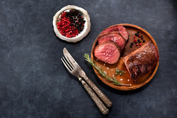 Roast beef on a wooden plate and spices