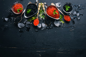Spoon with black and red caviar on a wooden background. Top view. Free space for text. - obrazy, fototapety, plakaty