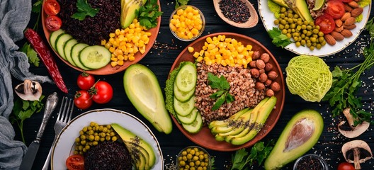 Healthy food. Black rice, buckwheat, avocado, cherry tomatoes, green peas and hazelnut. On a wooden background. Top view. Free space for your text.