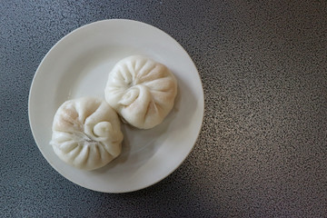 two chinese steamed buns or dumpling on dish with copy space background.