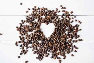 Coffee beans with annis on white wooden table.