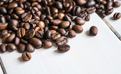 Close up of many coffee beans with annis on white wooden table.