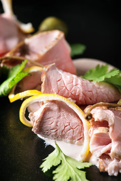 Vitello tonnato italian dish. Thin sliced veal with tuna sauce, capers and coriander served on black plate. Close up