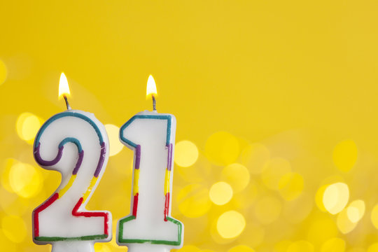 Number 21 birthday celebration candle against a bright lights and yellow background