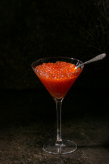 Glass of red caviar over dark background. Elegant food