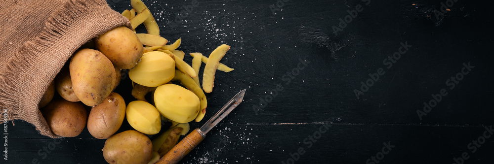 Wall mural raw potatoes on a black wooden background. cooking. free space for text. top view.