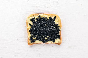 Sandwich with black caviar and butter. On a wooden background. Top view. Free space for text.