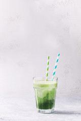 Glass of three color layer green spinach kale apple yogurt smoothie with retro cocktail tubes over gray background. Healthy vegan detox eating. Copy space. Toned image