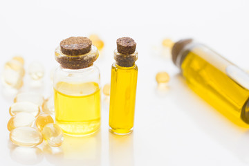 Natural cosmetics concept, essential oil in glass bottles and vitamin pills, white background, close up